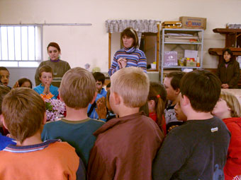 Professores e alunos rezando na sala de aula
