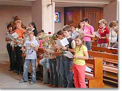 Mtter und Kinder freuen sich im Gottesdienst. Blumen werden als Ausdruck des Dankes zum Altar getragen