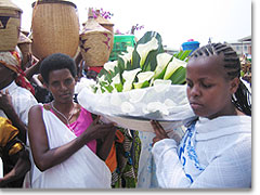 Jacky aus Kenia (rechts) und Frau Gaudence aus Burundi (links) bringen der Gottesmutter ein großes Blumengesteck zum Dank
