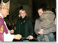 Bischof Lettmann spricht liebvoll mit den kleinen Kindern dieser Familie