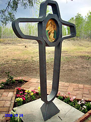Der Bildstock hat eine originelle Gestalt: die Kontur eines Kreuzes der Einheit, in der Mitte das Bild der Dreimal Wunderbaren Mutter von Schönstatt in einem Achteck