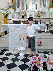 Gastón, das erste Kind, das 1998 als Frühchen den Besuch der „kleinen Gottesmutter“ erhielt, mit der Jubiläumsfahne